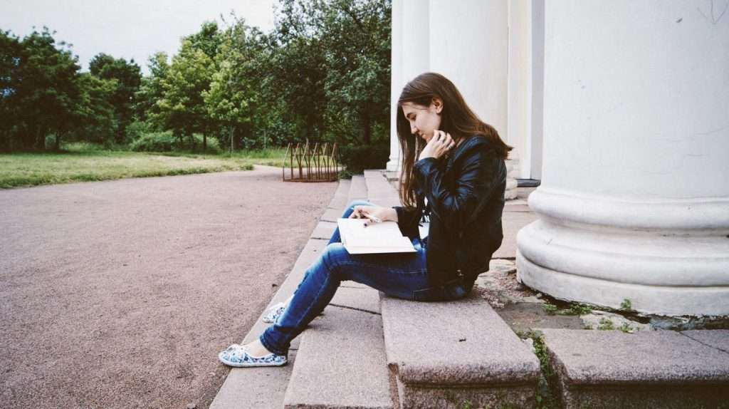 women reading on steps in park