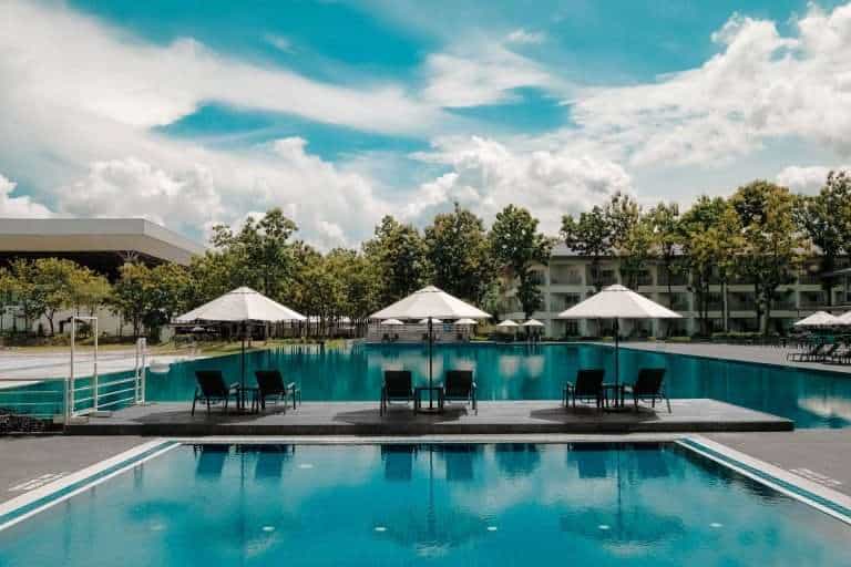 hotel pool with cabanas and tall trees in the background to demonstrate the best hotel rewards programs