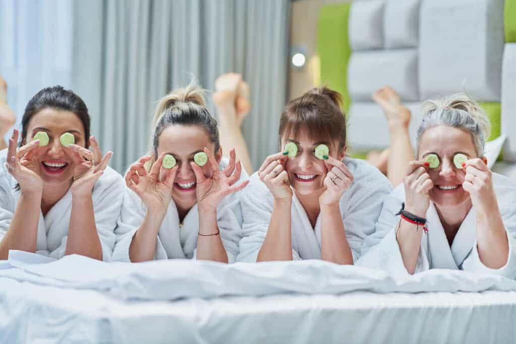 Family Vacation Ideas with Teenagers, 4 women in spa robes laying down with cucumbers on their eyes.
