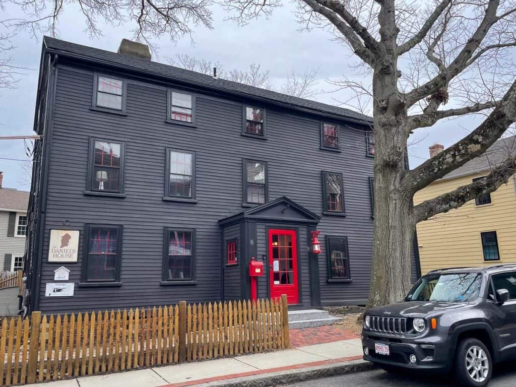 Daniels House, a black wood 3 story house with a red door