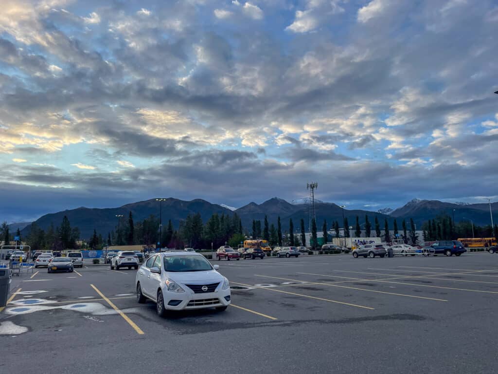 Parking lot in Anchorage that has a mountain and blue cloudy skies at sunset.