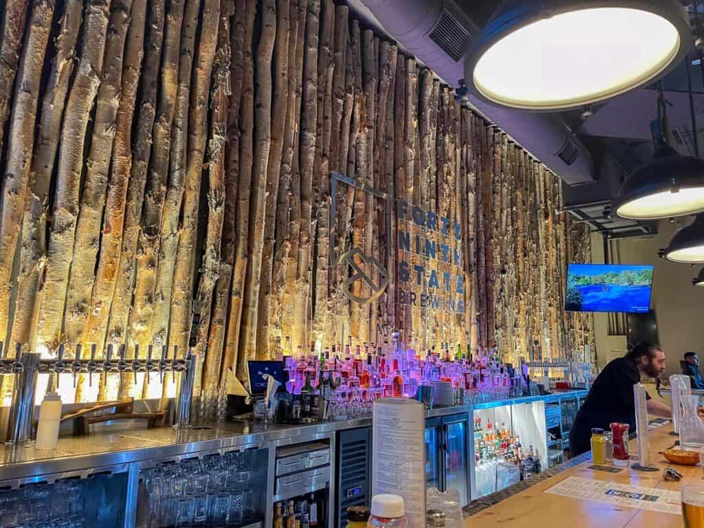 Inside of the 49th St Brewing company, a bar with aspen trees on the wall