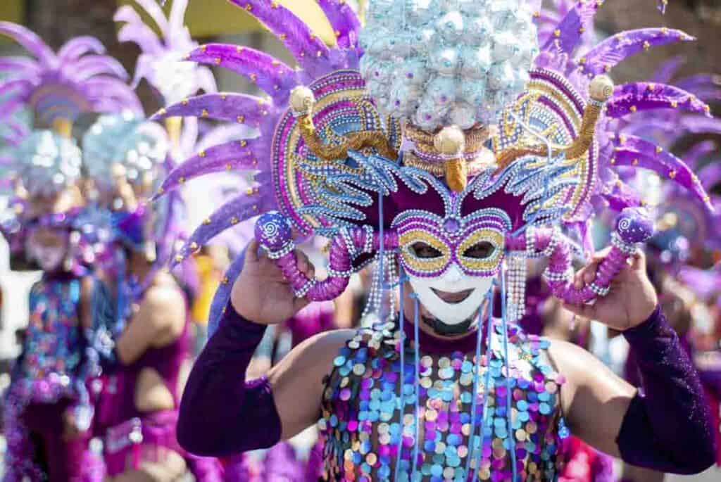 When to visit new orleans depends on what you want to see. Picture of Mardi Gras with elaborate purple and gold mask, sequins and feathers.