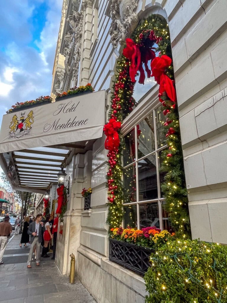 The exterior of Hotel Monteleone is decorated for the holidays with garlands, red bows, ornaments, and lights around the windows—a festive sight to enjoy while exploring things to do in New Orleans with teens under the striped awning.