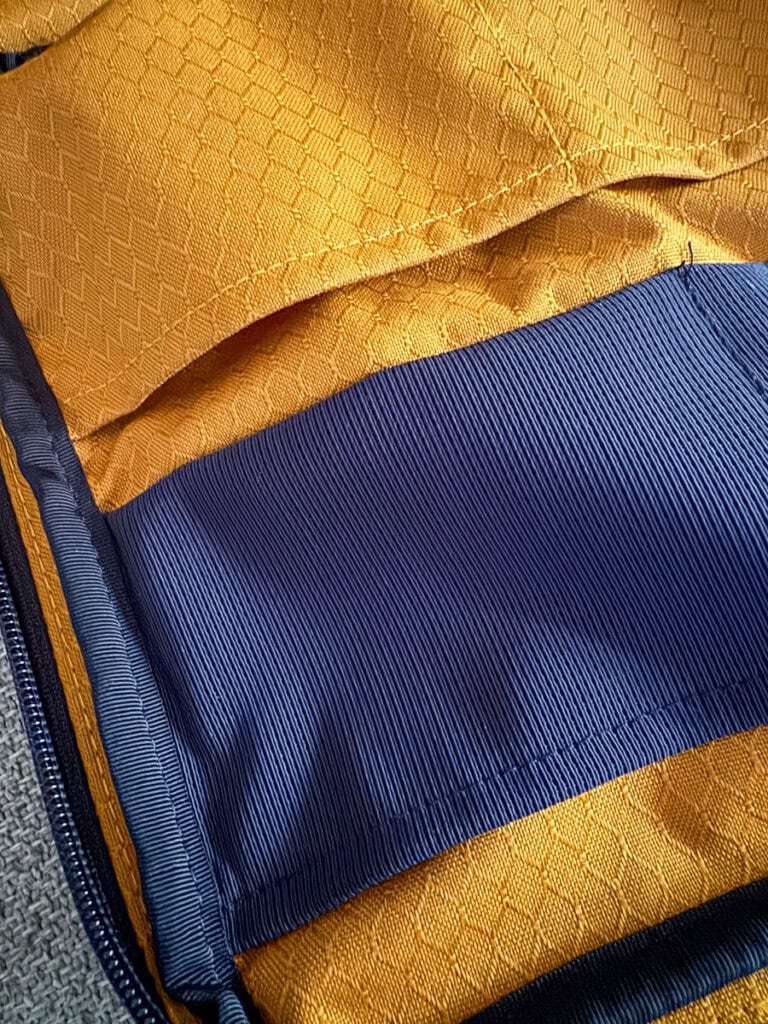 Close-up of a fabric with two sections: a textured yellow top and a smooth blue fabric with vertical ridges below, separated by blue trim—details often found on the best underseat bags for frequent flyers.